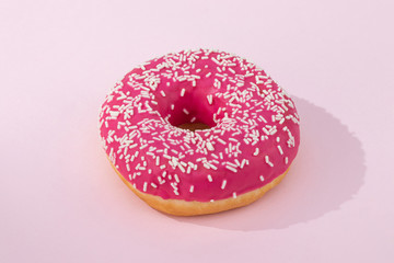 Pink donut with icing on pastel pink background