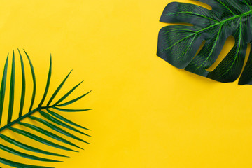 Fototapeta na wymiar Flat lay green leaves of palm tree on yellow background. travel concept