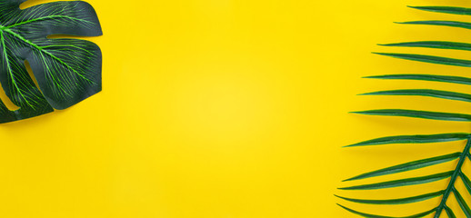 Fototapeta na wymiar Flat lay green leaves of palm tree on yellow background. travel concept