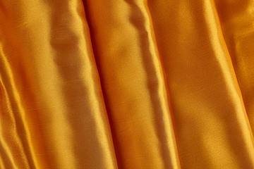 Gold shiny satin background with wave. Close up.