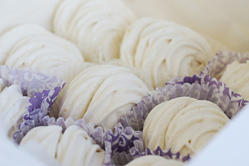 Marshmallows in paper packaging, laid out in rows.Home made zephyrs.