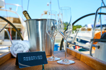 Obraz premium Romantic luxury evening on cruise yacht with champagne setting. Empty glasses and bottle with champagne and tropical sunset with sea background
