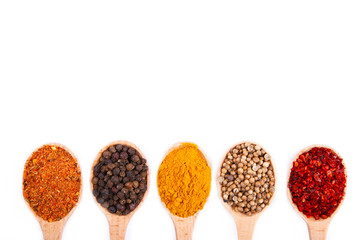 Spices mix on wooden spoons on a white wooden background. Top view