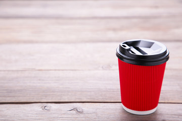 Red paper cup of coffee on grey wooden background