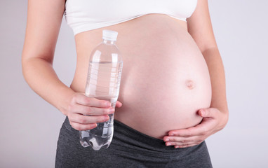 Young pregnant woman holding a bottle of water