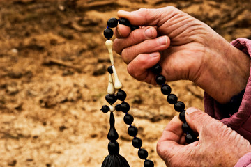 Rosary in old grandmother's hands closeup