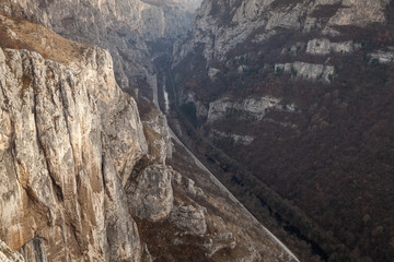Amazing high angle view of narrow gorge and canyon with sunlit, steep, rocky cliffs raising above river, road and railroad