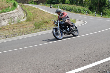 Man riding a classic motorcycle on highway of mountain