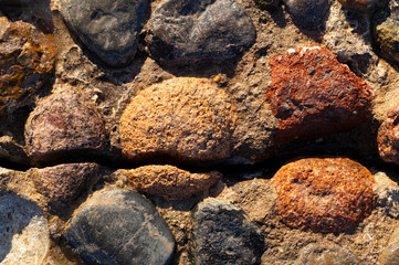 Background of colored stones. The surface is decorated with natural material. Pattern on the floor of multicolored pebbles.