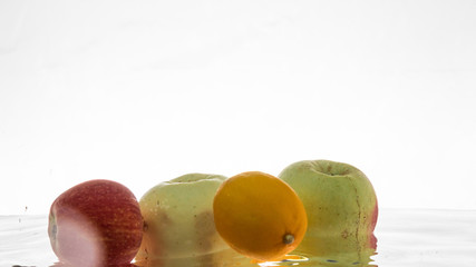 Still life of ripe fruit under water, on a white background. Clean and fresh fruit in the water. Natural fruits.