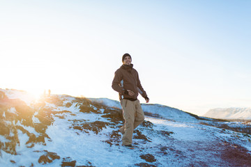 The guy walks through the snowy rocks. Beautiful Iceland in winter
