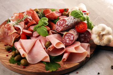 Food tray with delicious salami, pieces of sliced prosciutto crudo, sausage and basil. Meat platter
