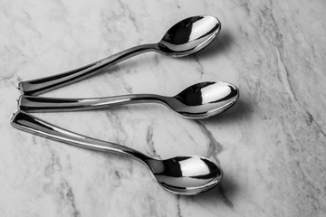 Cucharas de plata de varios tamaños, acomodadas sobre una superficie de marmol blanco de forma artistica