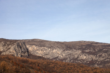 Naklejka na ściany i meble Rocky peaks and vivid autumn colors of the forest on Svrljig (Svrljiske) mountains in Serbia under a clear blue sky