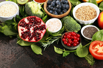 Healthy food clean eating selection: fruit, vegetable, seeds, superfood, cereals, leaf vegetable on rustic background