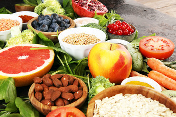 Healthy food clean eating selection: fruit, vegetable, seeds, superfood, cereals, leaf vegetable on rustic background