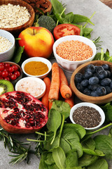 Healthy food clean eating selection: fruit, vegetable, seeds, superfood, cereals, leaf vegetable on rustic background