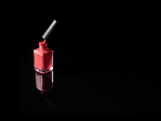 Pink nail polish bottle opened on black background with refection