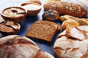 Assortment of baked bread and bread rolls and cutted bread on table background