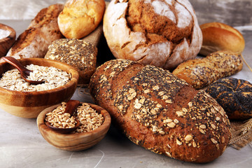 Assortment of baked bread and bread rolls and cutted bread on table background