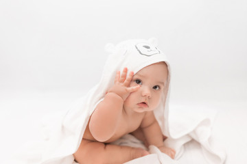 Fototapeta na wymiar Cute baby under a white towel with a hood after a bath. Baby in a towel. Children's portrait. Healthcare concept.