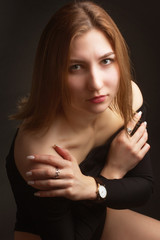 Portrait in the photo Studio of a brown-haired girl, on a black background in black clothes with open shoulders. Short hair.