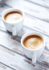  Two cups of coffee on bright wooden background.