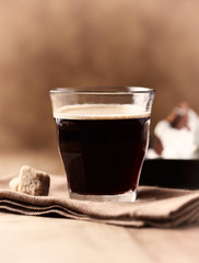 Coffee in glass cup on brown wooden background. Close up.