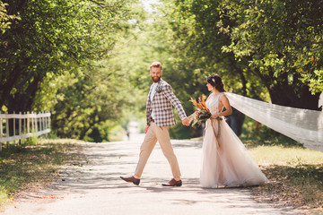 Lovely wedding couple wood forest. Bride and groom, follow me, married couple, woman in white wedding dress and veil. Rustic outdoors love story. Follow me hipster photo. newlyweds holding hand walk
