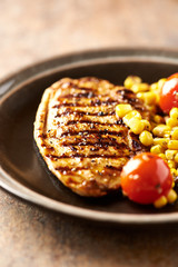 Grilled Turkey Breast with sweet corn. Rustic background. Close up.