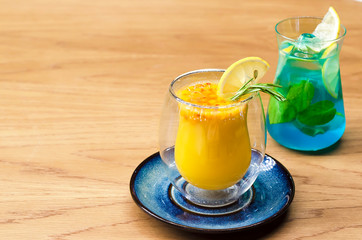 hot winter sea-buckthorn tea with citrus fruits and rosemary in a double-walled glass. Cold summer mint blue cocktail with ice and lemon. contrast drinks. soft focus