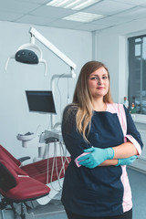 Fototapeta na wymiar Beautiful female dentist standing in the dentistry near dental unit, smiling at the camera and ready ready to accept a new patient in clinic, healthy teeth concept