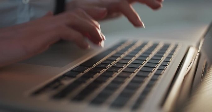 Female hands type on laptop keyboard touching touchpad. No face woman sits on sofa freelancing working at home writes post comments in social networks.