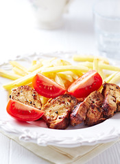  Fried pork tenderloin with tomatoas and french fries. Bright background