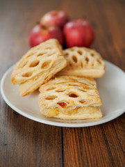 Apple lattice on a white plate on a wooden table, red apples in the background., Selective focus, Pastry product.,