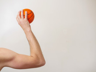 Mini basketball in a muscular hand ready to throw, Copy space, light background.