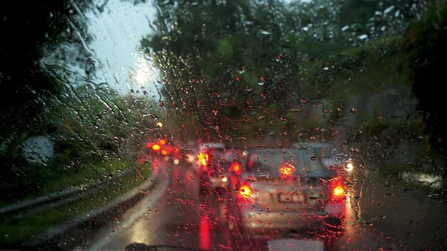 heavy rain and traffic jam from inside a car  POV shot from inside car  of rainy day on the road wipers cleaning wind shield 