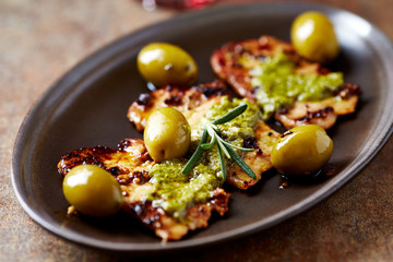Fried pork with green olives and fresh rosemary. Concept for a tasty meal. Rustic background