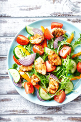 Healthy Salad with Chicken Briest, Cherry Tomatoes, Cucumber, Rocket and fresh Basil. Bright wooden background. Top view.