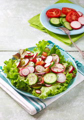 Healthy Salad with Cherry Tomatoes, Green Olives, Radish, Leek, Lettuce and Fresh Basil. Easy summer snack. Bright wooden background.
