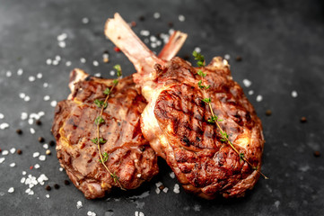 two steaks - grilled beef tomahawk with spices,  stone background.