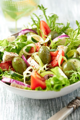 Salad with Green Olives, Tomatoes, Endive, Cucumber and Feta Cheese. Wooden background.