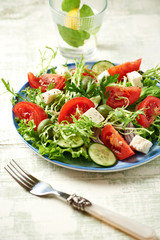 Salad with Green Olives, Tomatoes, Endive and Feta Cheese. Bright Wooden background. Close up.