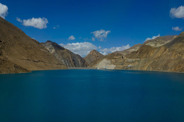 Fototapeta na wymiar AERIAL: Breathtaking view of a large deep blue lake by the Manak Dam in Tibet.