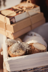 Vintage winter floral composition with white chair, books, basket with cones, birch saw cuts on a blanket. Winter floristic
