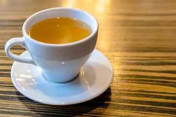 A white Cup of tea on a wooden table in a cafe close-up. 
