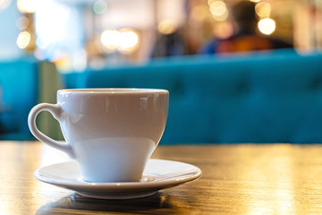 A white Cup of tea on a wooden table in a cafe close-up. 
