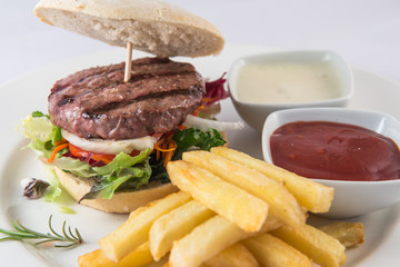 Detail of a hamburger with fries on a plate