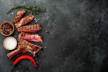 steak - sliced ​​grilled beef tomahawk with spices on a stone background. with copy space for...
