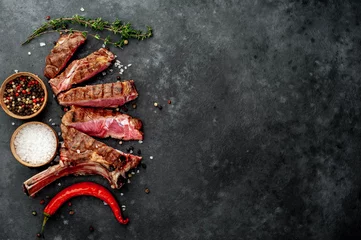 Selbstklebende Fototapeten steak - sliced ​​grilled beef tomahawk with spices on a stone background. with copy space for your text © александр таланцев